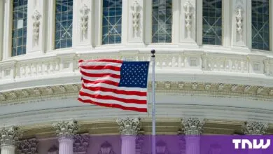 An American flag waves proudly in front of the ornate white architecture of the US Capitol dome.