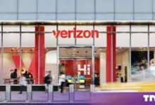 Exterior view of a modern Verizon storefront featuring a bold red logo and glass windows.