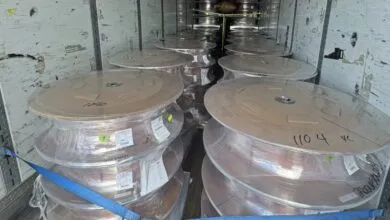 Inside view of a semi-truck trailer packed with large spools of copper wire wrapped in plastic.