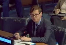 A man in a suit and glasses seated at a UN conference table labeled Russian Federation