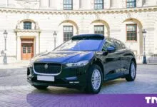 Black Wayve Jaguar I-Pace autonomous test car parked on a London cobblestone street.