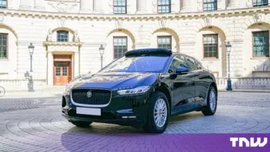 Black Wayve Jaguar I-Pace autonomous test car parked on a London cobblestone street.