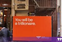 An orange Whop billboard on a New York street reads You will be a trilionaire, with a blurred pedestrian passing.