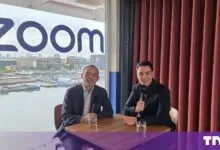 XD Huang and Cristian Dina sitting at a table with microphones in front of a Zoom logo window.
