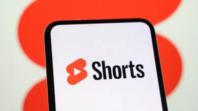 Smartphone screen displaying the red YouTube Shorts logo against a bright red and white background