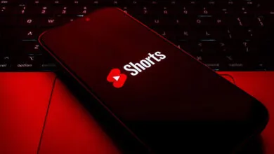 YouTube Shorts logo displayed on a smartphone screen resting on a red backlit laptop keyboard