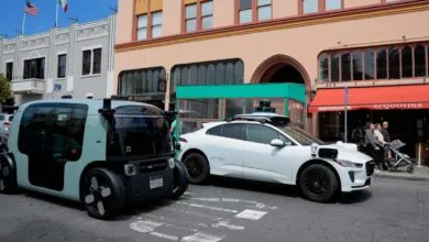 Autonomous Zoox and Waymo self-driving vehicles parked on a city street.